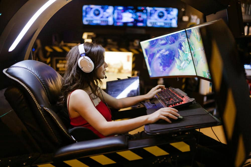 a girl plays a videogame on three monitors