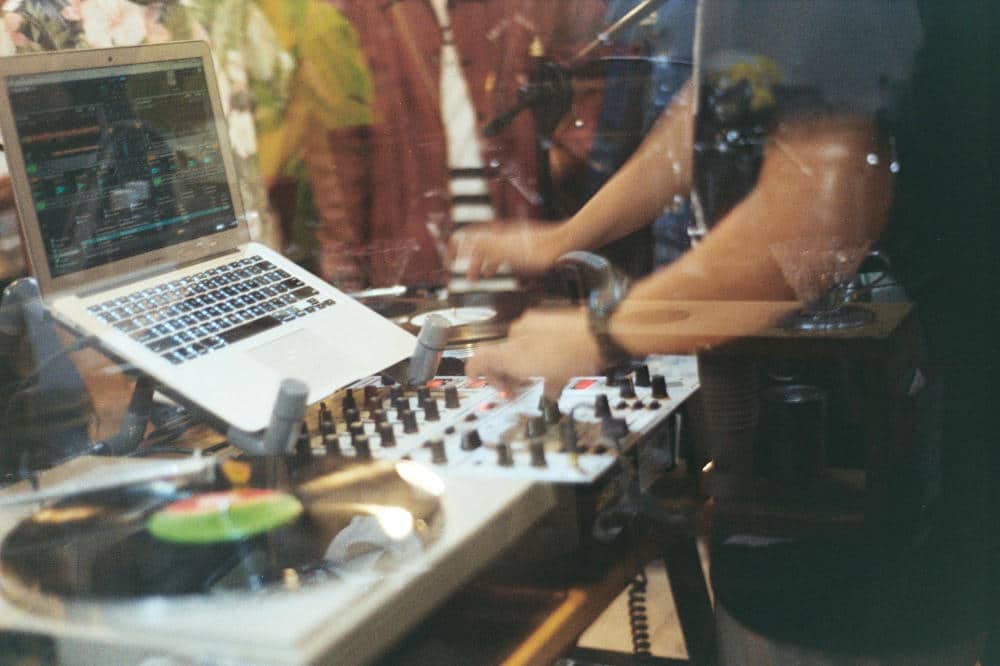 dj playing music with turntables and laptop