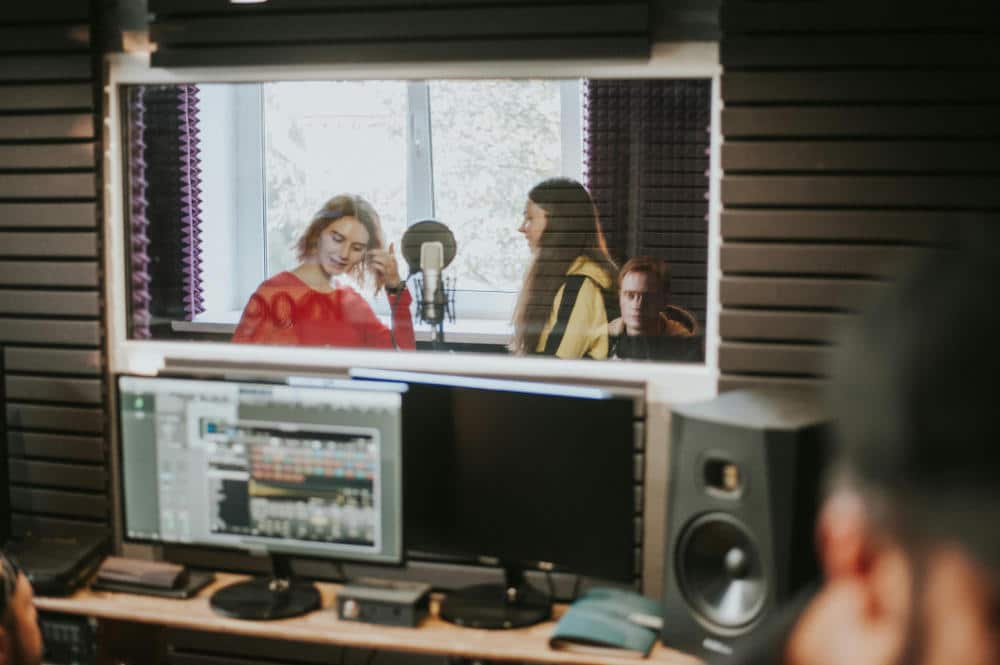 two female singers recording vocals in a music studio